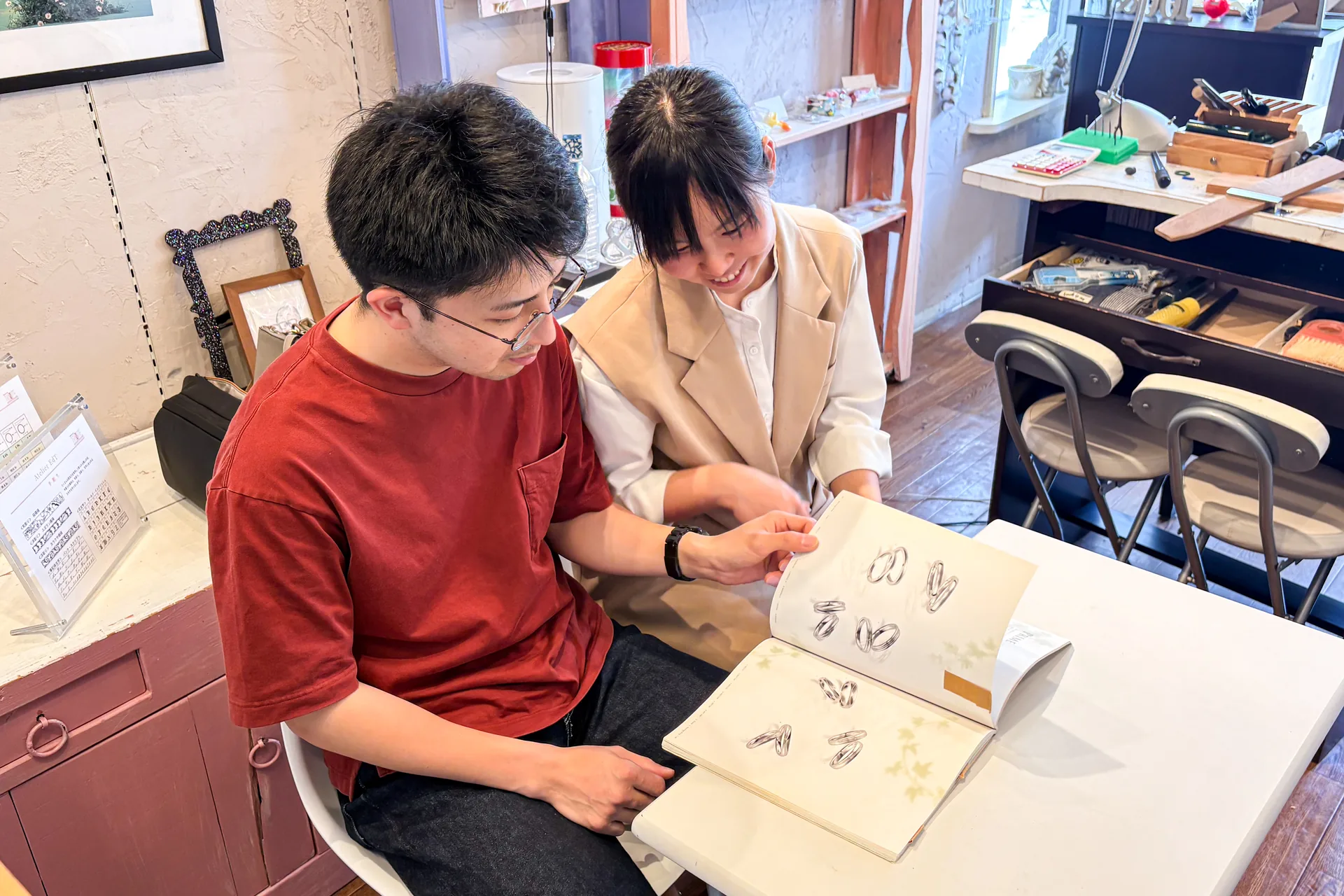 デザイン見本帳を見ながら結婚指輪のイメージを膨らませるカップル｜アトリエ100&1