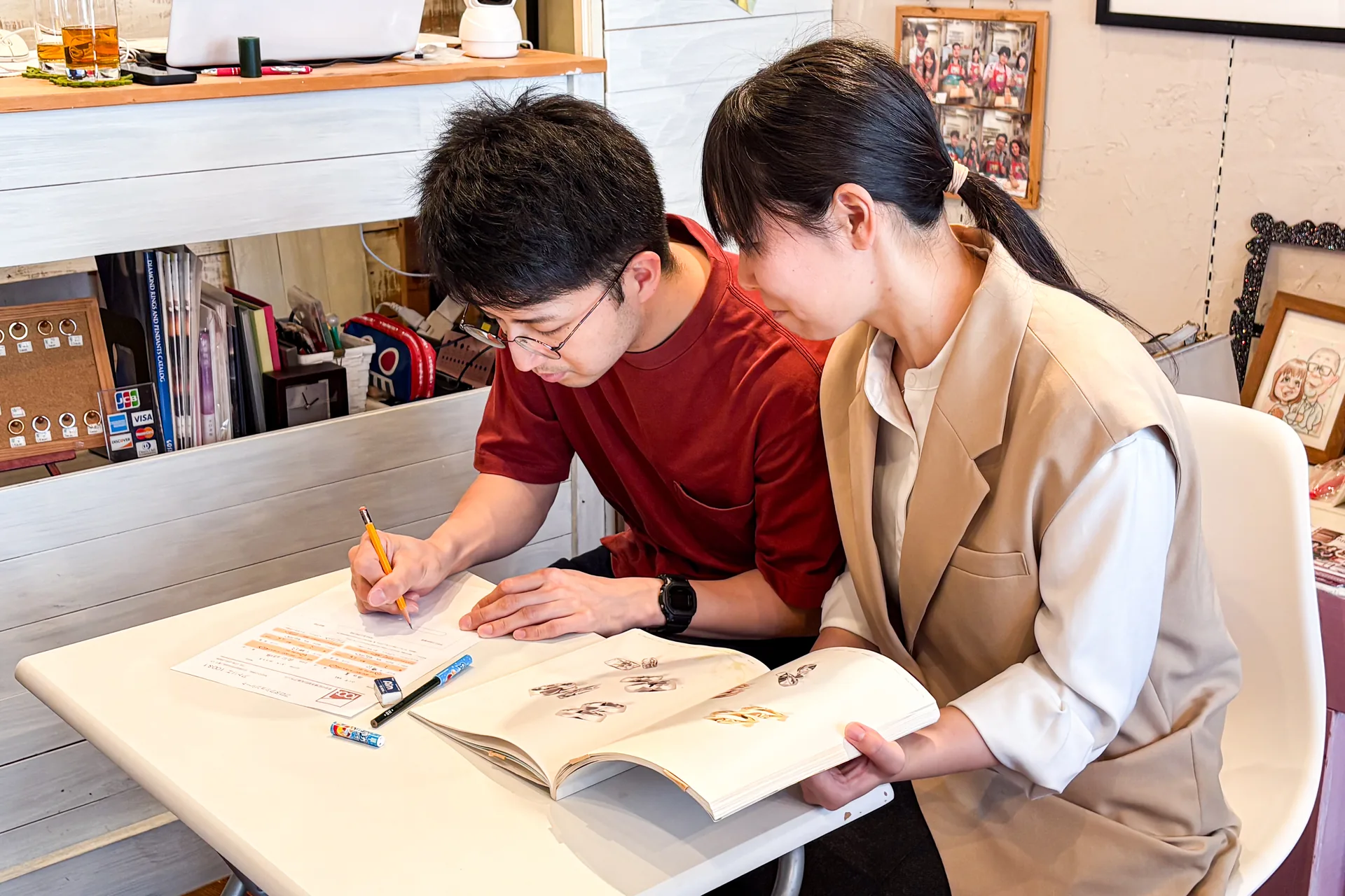 二人でデザイン見本帳を見ながら相談する手作り指輪のカップル