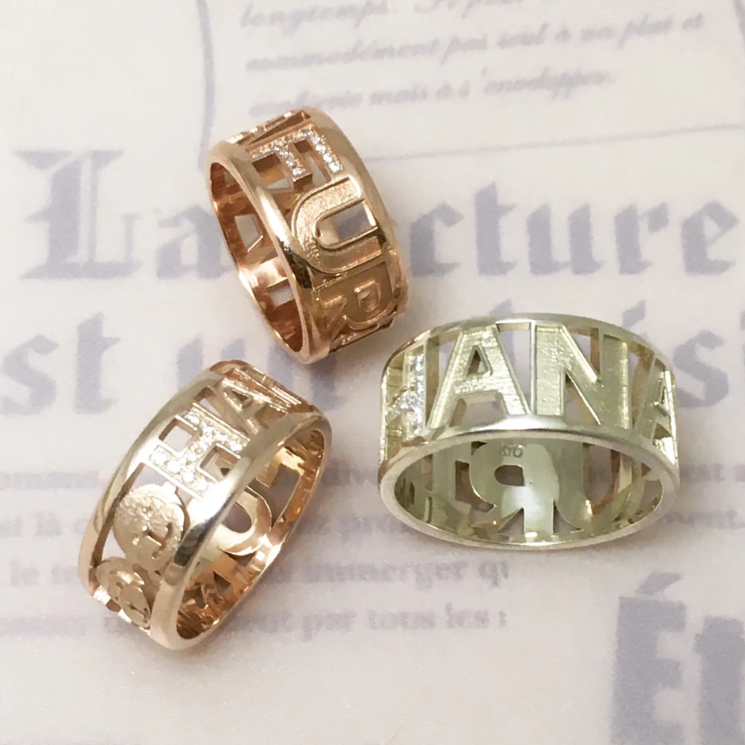 手作り結婚指輪の作例。イエローゴールドとローズゴールドで名前を透かし彫りにした幅広リング。ダイヤをあしらったオーダーメイドの一例