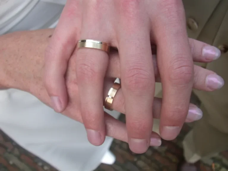 ペアで結婚指輪を着けたふたりの手元アップ。ゴールドの手作り結婚指輪を重ねた、日常の装着イメージが伝わるハンドショット